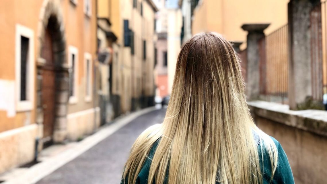 a woman with long blonde hair walking down a street